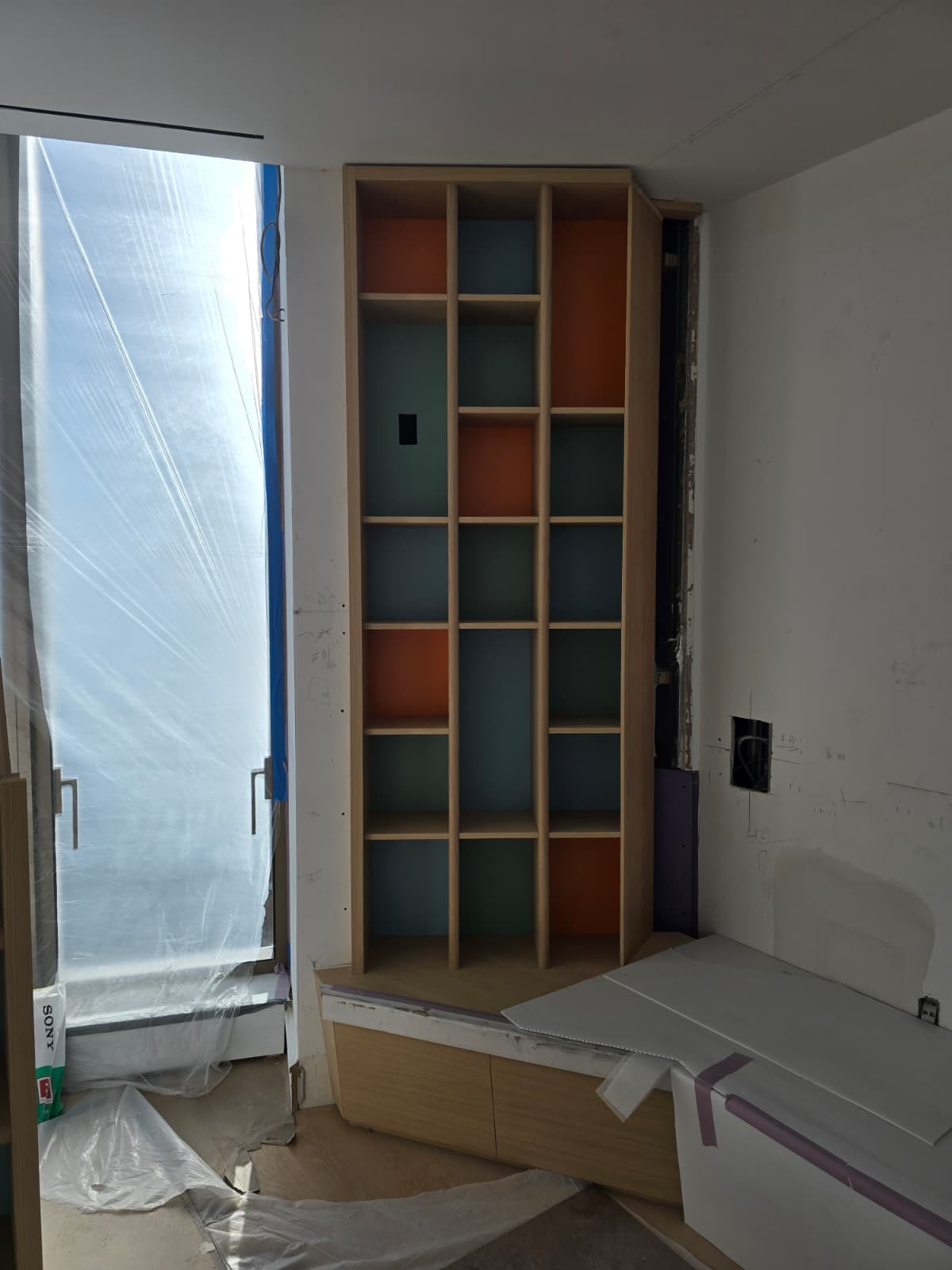 Custom built-in corner bookcase with orange and blue painted niches