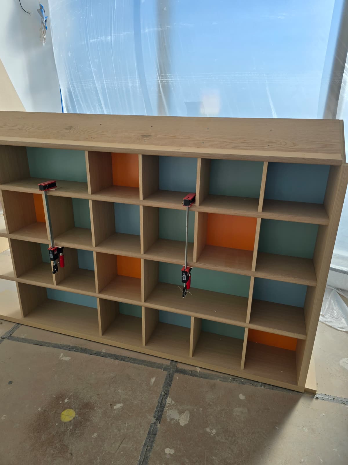 Wooden cubby shelving unit with painted backs during installation